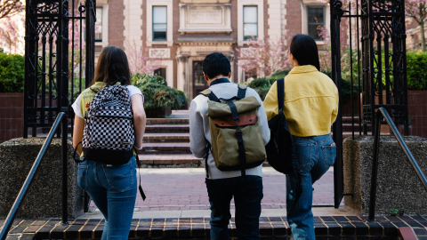 students with backpacks walk through campus